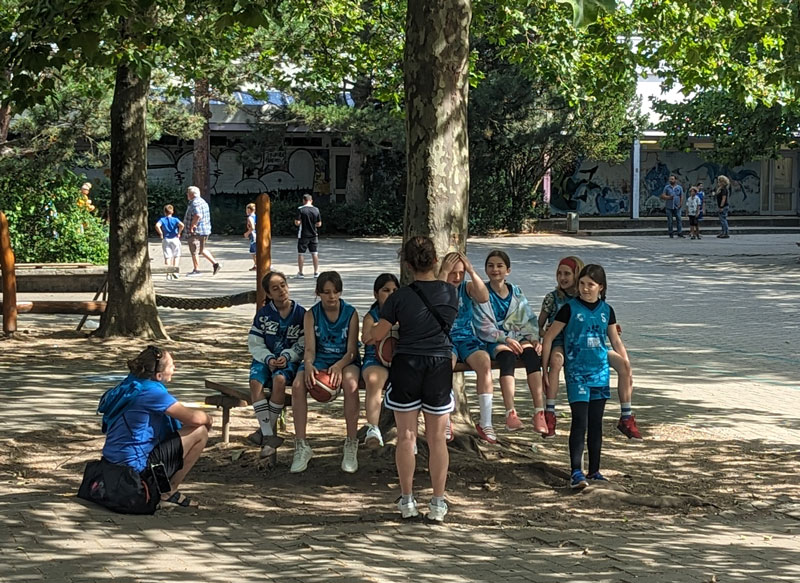 Die Mädchen sitzen um einen Baum im Schulhof und besprechen sich gemeinsam vor dem Turnier