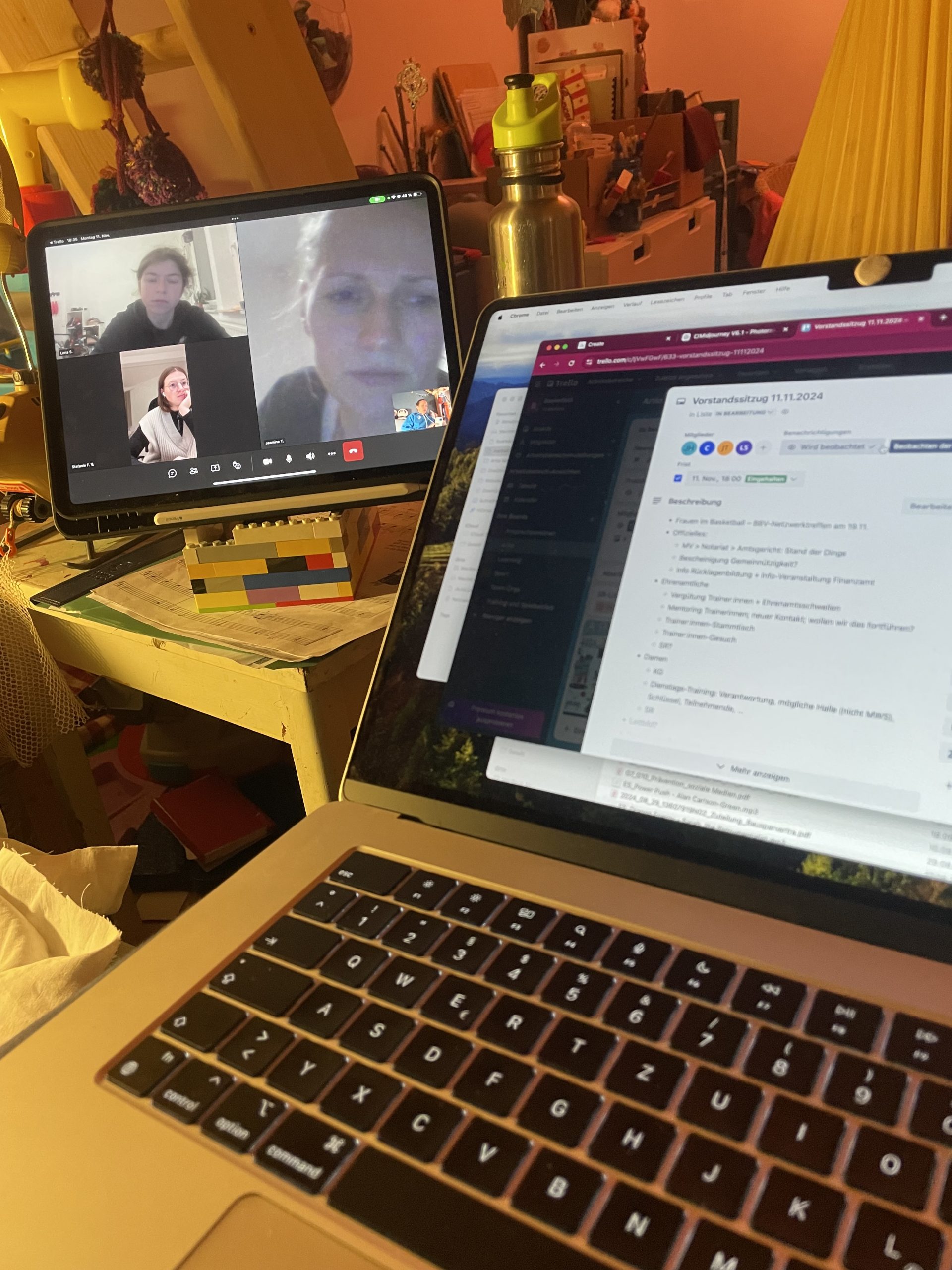 Zwei angeschnittene Bildschirme: einer zeigt das Meeting mit den Gesichtern des Vorstands, der andere die Tagesordnung