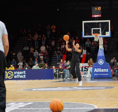 U10-Trainerin wirft einen Basketball von der Mittellinie bis zum Korb … und verfehlt ihn dreimal knapp.