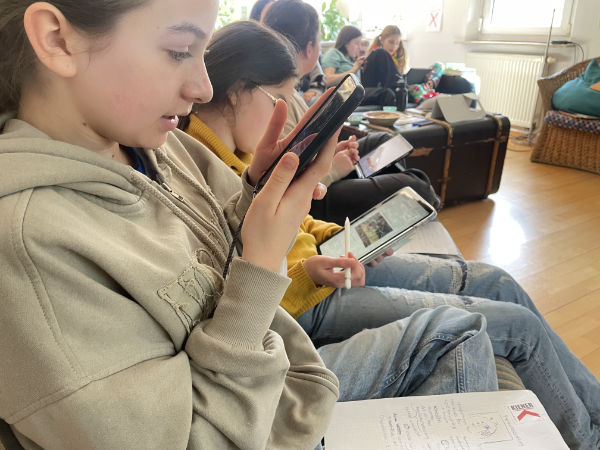 Die Junior-Schiedsrichterinnen sitzen zusammen und bearbeiten am Tablet ihre Aufgaben